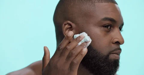 black man padding skin with face cloth