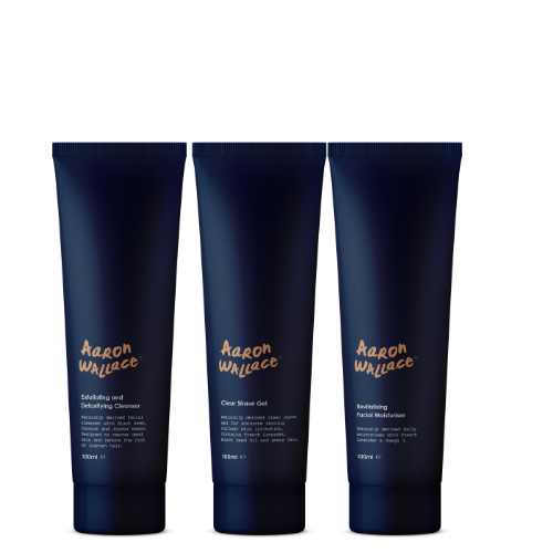 Three blue bottles of Aaron Wallace skincare system on a white background