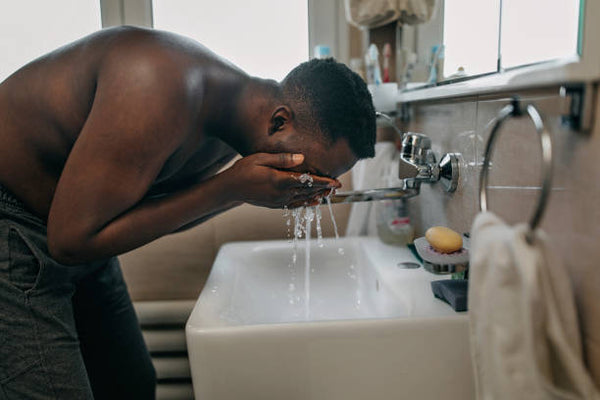 black man washing face in sink